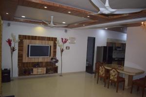 a living room with a tv and a table and chairs at Jannat Villa by Book Ur Stay in Lonavala