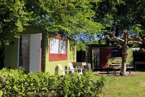 a green tiny house with a table and chairs at Landgoedboerderij Oosterheerdt in Leek +16 photos