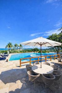a table with an umbrella next to a swimming pool at Villa Nautilus Be Happy in Fortaleza