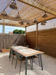 a wooden table and chairs under a pergola at LE TERRACOTTA COTE D'AZUR - Proche PLAGE - Terrasse & Confort - CLIM - Parking et Wifi Gratuit- OFFRE SPECIALE in Fréjus