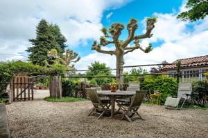 a patio with a table and chairs and a tree at Gite La Forge in Le Buisson de Cadouin