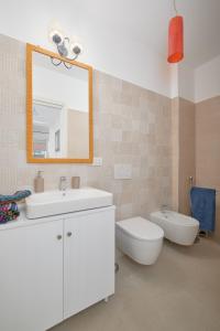 a bathroom with a sink and a toilet and a mirror at Casa vacanze vento di mare in Alghero +11 photos
