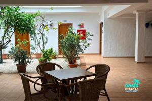 a table and chairs in a room with potted plants at Hotel Oasis Atalaya in Conil de la Frontera