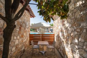 a table and chairs with an umbrella in an alley at Almyra Holiday Village in Edipsos