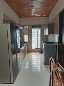 a kitchen with stainless steel appliances and white tile floors at Jannat Villa by Book Ur Stay in Lonavala