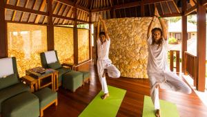 two women are doing yoga in a room at Qunci Villas Resort in Senggigi