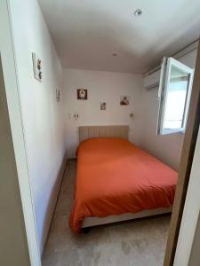 a small bedroom with a red bed in a room at Les clés de Jules in Gruissan