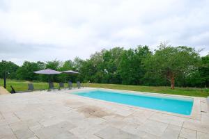 a swimming pool with chairs and umbrellas at Gite de l'Egal in Le Buisson de Cadouin