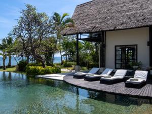a resort with a pool with lounge chairs next to it at Villa Bossi Bali at Tanguwesia in Bubunan