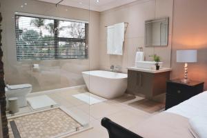 a bathroom with a tub and a sink and a toilet at Palmera Guest House in Krugersdorp