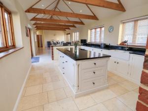 a large kitchen with white cabinets and black counter tops at The Stables at Hall Barn in Diss