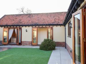 a house with a green lawn in front of it at The Stables at Hall Barn in Diss