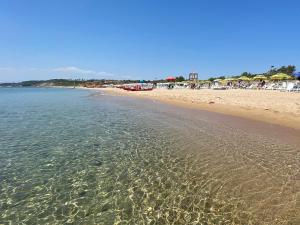 a beach with a group of people in the water at Cala Longa Poseidon Beach Resort in Casa dello Stumio