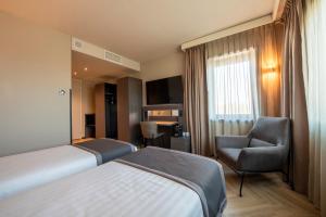 a hotel room with two beds and a chair at Bastion Hotel Dordrecht Papendrecht in Dordrecht