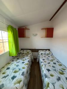 two beds in a small room with green curtains at Casita la Loma in Cádiz