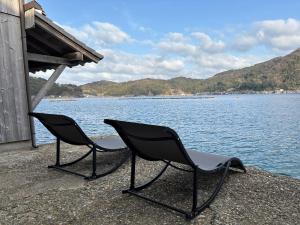 two chairs sitting next to a body of water at 伊根の舟屋 樹 Funaya Inn Tatsuki , Ine in Kameshima