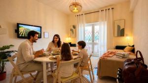 a family sitting around a table in a living room at Refúgio na Praia de Santa Cruz- A poucos passos da praia, surf e restaurantes in Santa Cruz