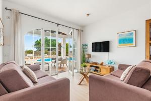 a living room with two couches and a table and a television at Villa Rouss by Escape Home in Cala en Porter