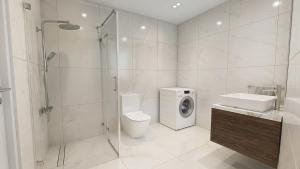 a bathroom with a shower toilet and a washing machine at Ferienwohnung Apartment am Moosrain in Eitting +18 photos