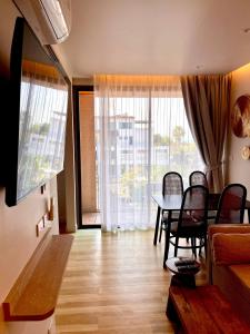a living room with a table and chairs and a large window at Coconut Suite Aonang in Ao Nang Beach