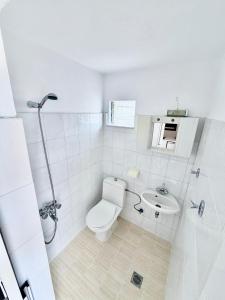 a white bathroom with a toilet and a sink at Cleopatra's House Apartments in Archangelos