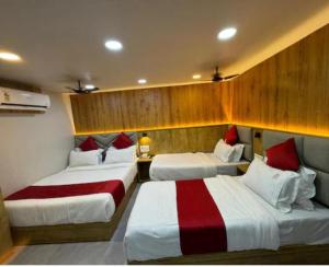 a bedroom with three beds with red and white sheets at Hotel Baghdad Palace in Mumbai
