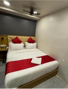a bedroom with a bed with red and white pillows at Hotel Baghdad Palace in Mumbai