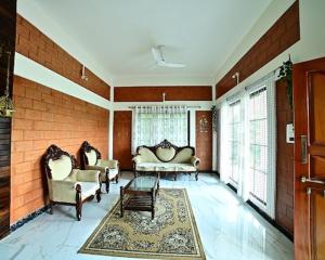 a living room with two couches and a rug at Assraya stay in Kushālnagar
