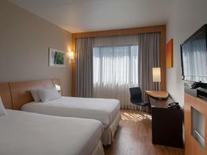 a hotel room with two beds and a television at Novotel Porto Alegre Tres Figueiras in Porto Alegre