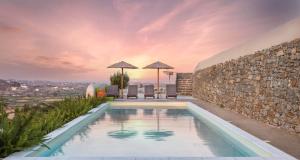 a villa with a swimming pool and a stone wall at Halcyon Suites and Villas Naxos in Naxos Chora