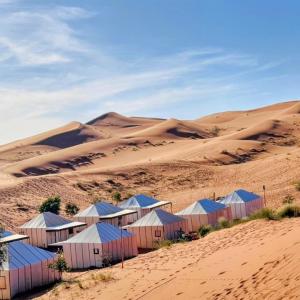 a group of huts in the sand in the desert at Sunset Dunes Luxury Camp in Merzouga