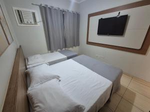 two beds in a room with a tv on the wall at Olímpia Temporada Cond. Villagio in Olímpia