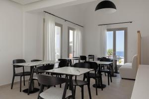 a dining room with tables and chairs and windows at Filomare Oia Suites in Oia