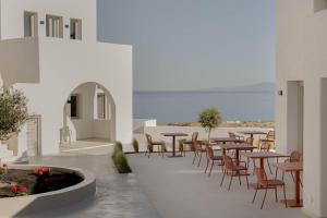 a patio with tables and chairs and the ocean at Filomare Oia Suites in Oia