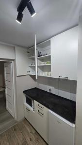a kitchen with white cabinets and a black counter top at Via VOLTA 2025 Refresh 2 Bedroom Apartment in Płock