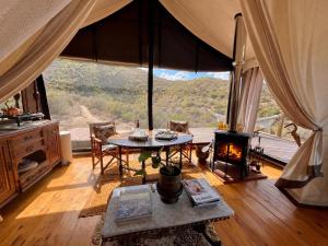 a living room with a table and a fireplace at Tula Retreat - Secluded Karoo Escape - Hot Tub - Private Boat Arrival in Calitzdorp