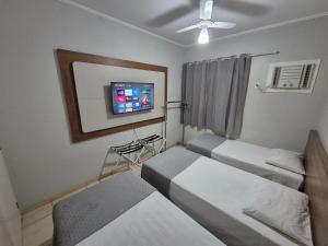 a room with three beds and a flat screen tv at Olímpia Temporada Cond. Villagio in Olímpia