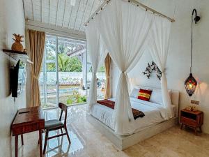 a bedroom with a canopy bed with a desk and a window at Hafrana Villa by AGATA - 700sqm 2BR Villa with Private Pool & Jacuzzi in Sidemen