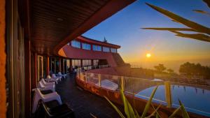 a building with a pool with chairs and the sunset at Hotel Carqueijais - Serra da Estrela in Covilhã