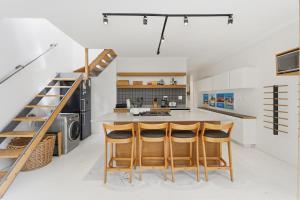 a kitchen with a staircase and a kitchen island with bar stools at Modern Cozy Upper Wynberg Cottage in Cape Town