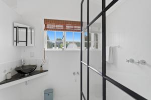 a bathroom with a sink and a glass shower at Modern Cozy Upper Wynberg Cottage in Cape Town +25 photos