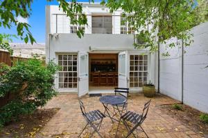 a patio with chairs and a table in front of a building at Modern Cozy Upper Wynberg Cottage in Cape Town