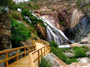 a wooden staircase leading to a waterfall in a canyon at Vía Láctea Costa da Morte in Dumbría