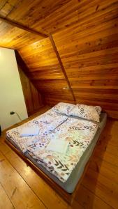 a bed in a room with a wooden wall at Chata pod Černou horou in Rudník
