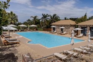 a swimming pool with lounge chairs and umbrellas at Almyra Holiday Village in Edipsos