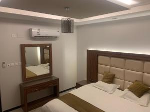 a bedroom with a bed and a mirror at الشرفة هوم للشقق المخدومة in Najran +11 photos