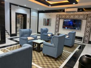 a waiting room with blue chairs and a flat screen tv at الشرفة هوم للشقق المخدومة in Najran