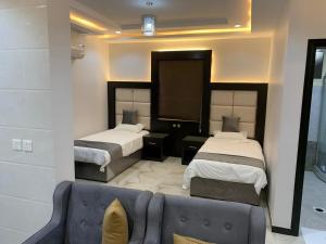 a hotel room with two beds and a couch at الشرفة هوم للشقق المخدومة in Najran