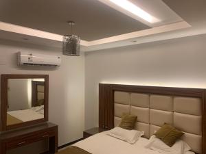 a bedroom with a bed and a large mirror at الشرفة هوم للشقق المخدومة in Najran
