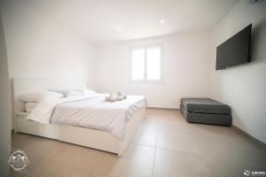 a white bedroom with a bed and a flat screen tv at Les Embruns - Mer - Terrasse in Le Grau-du-Roi